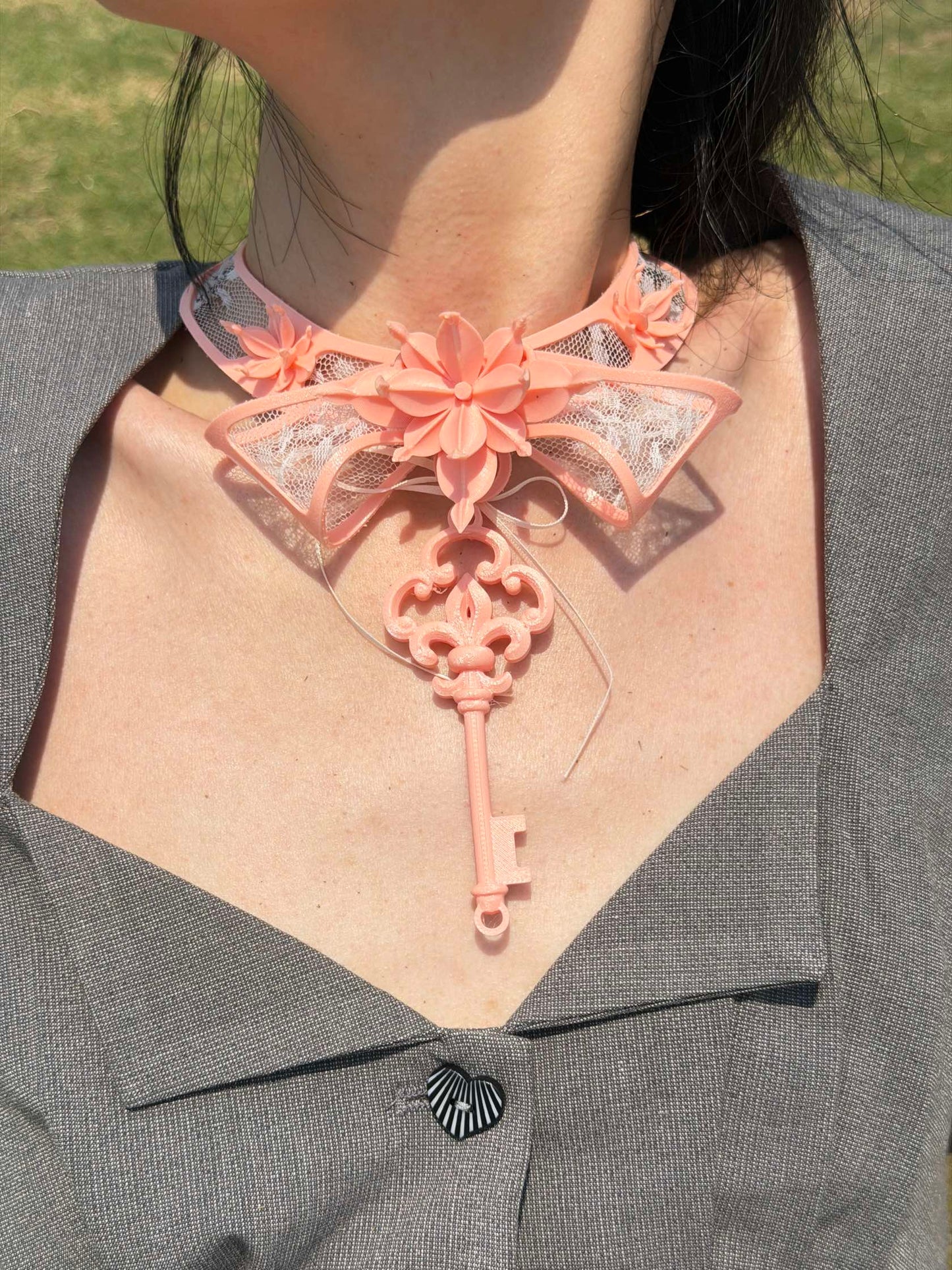 Pink lace key choker styled with a grey blazer — romantic statement necklace