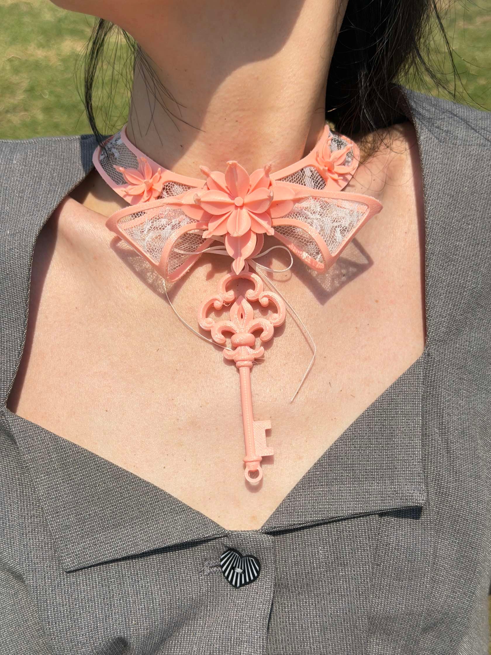 Pink lace key choker styled with a grey blazer — romantic statement necklace